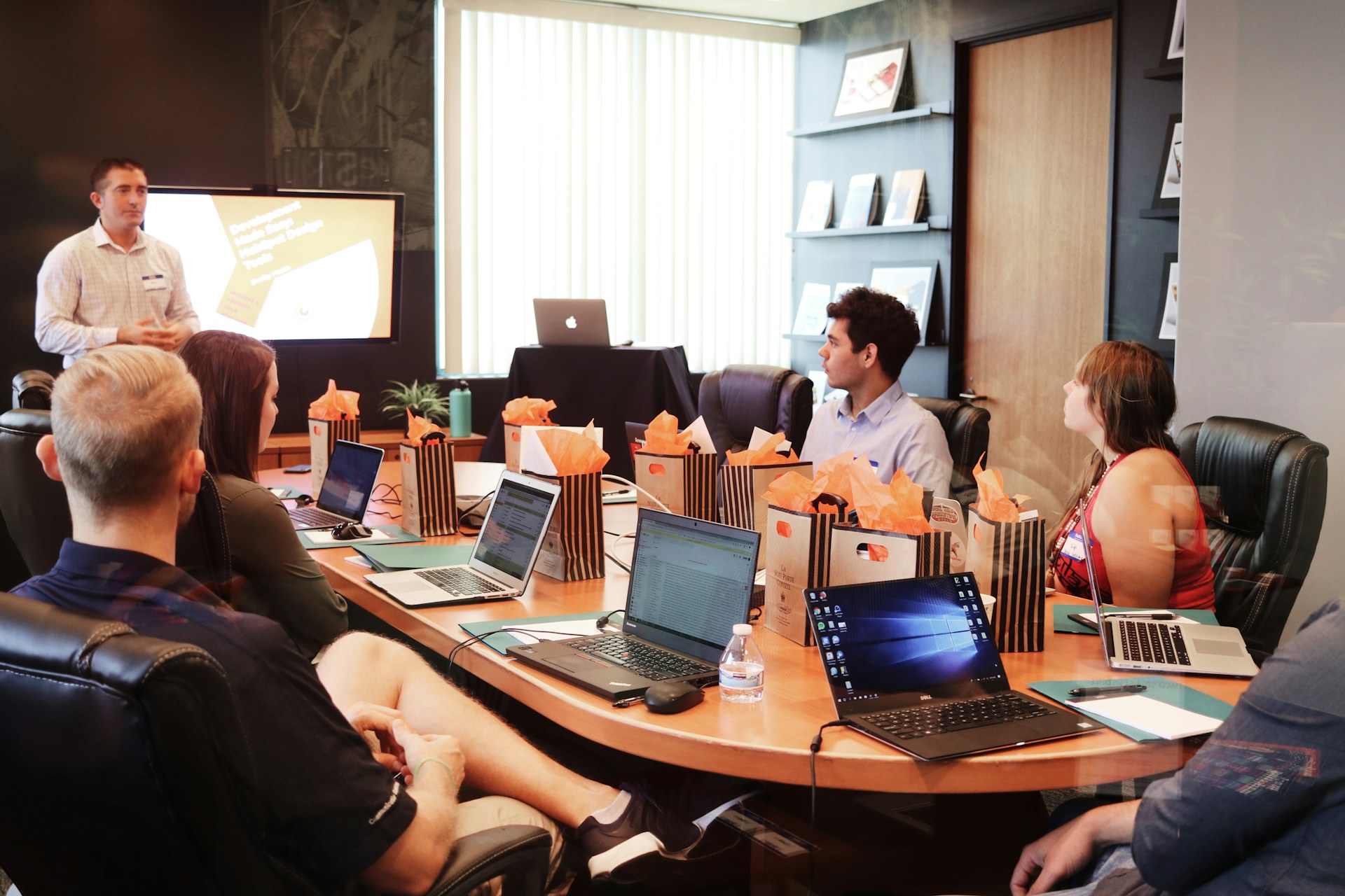 Ein Team bespricht ein Projekt an einem Tisch mit mehreren Laptops.